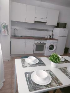 a kitchen with white appliances and white plates on a table at San Centro IFEMA Wizink Metropolitano Airport Apartments in Madrid