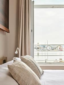 un letto con cuscini di fronte a una finestra di Otonali Hôtel by Breizh Café a Saint Malo