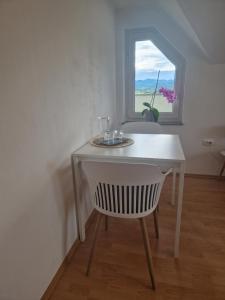 uma mesa branca com uma cadeira em frente a uma janela em Green House Apartment em Pivka