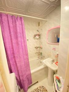 La salle de bains est pourvue d'un rideau de douche violet et d'un lavabo. dans l'établissement Комната с лоджией у Татьяны, à Jurmala