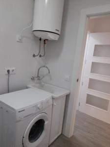 een wasmachine en droger in een witte wasruimte bij Puerta de la Bética in Mengibar