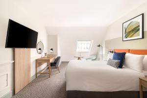 um quarto de hotel com uma cama grande e uma secretária em voco Edinburgh - Royal Terrace, an IHG Hotel em Edimburgo