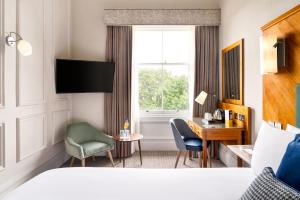 a hotel room with a bed and a desk and a window at voco Edinburgh - Royal Terrace, an IHG Hotel in Edinburgh