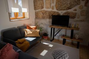 a living room with a couch and a flat screen tv at Casa das Tias in Baltar