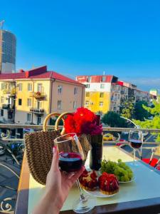 een persoon met een glas wijn op een tafel met voedsel bij Eiffel Hotel in Batoemi