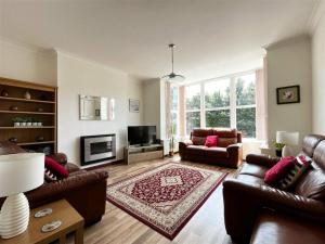 a living room with leather couches and a television at High Gables Apartment 2 in Paignton