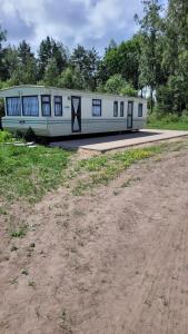 a white train car parked next to a dirt road at Dvēseles veldzes dārzs in Ziemupe