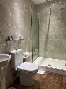 een badkamer met een douche, een toilet en een wastafel bij The Tudor Hotel in Bridgwater