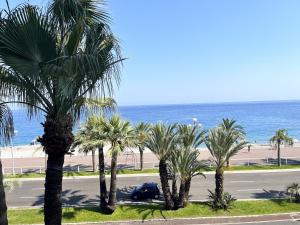 una strada con palme di fronte a una spiaggia di Promenade-des-anglais-front-sea a Nizza