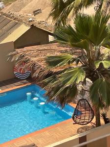 a swimming pool with a palm tree next to a house at LA SUNSET in Accra
