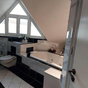 a bathroom with a tub and a toilet and a window at Ferienwohnung DG in Altenkunstadt