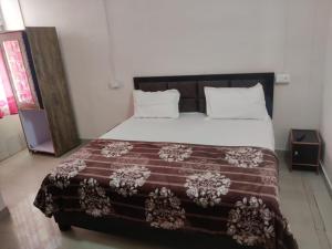 una camera da letto con un grande letto con una coperta marrone di Apna Guest House Dehradun a Dehradun