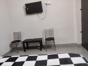 um quarto com duas cadeiras e uma mesa e uma televisão em Apna Guest House Dehradun em Dehradun