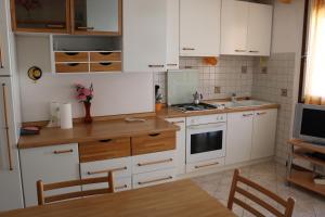 Appartamento Giove في بيبيوني: مطبخ بدولاب بيضاء وقمة كونتر خشبي