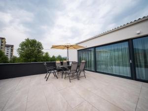 eine Terrasse mit einem Tisch, Stühlen und einem Sonnenschirm in der Unterkunft Villa AURORA in Sarajevo