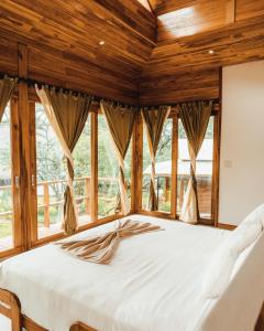 Cama en habitación con techos y ventanas de madera en Mellow Resort, en Gemastepe