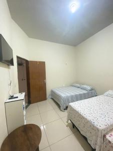 a hotel room with two beds and a television at Pousada Mineira in Barreirinhas