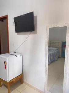 Habitación con espejo y TV en la pared. en Pousada Mineira, en Barreirinhas