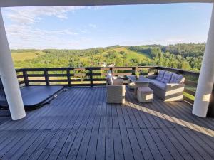 a deck with a couch and a table and chairs at Daj Spokój w Bieszczadach - całoroczny 7 osobowy domek z Jacuzzi in Polańczyk