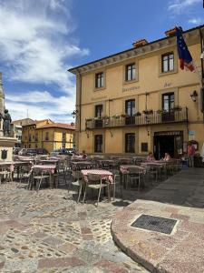 un grupo de mesas y sillas frente a un edificio en Hostal Restaurante Boccalino, en León
