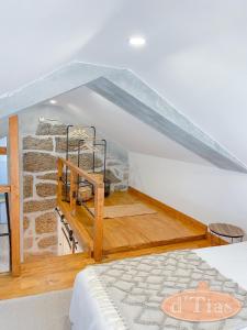 a attic room with a bed and a stone wall at Casa das Tias in Baltar