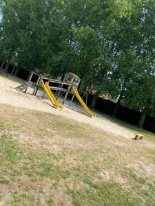 um parque infantil com um escorrega amarelo num campo em camping des crocs em Saint-Quentin-en-Tourmont
