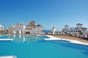 a large swimming pool with white buildings in the background at Apartment Marina Alcaidesa 2 beds Golf & Beach in La Alcaidesa