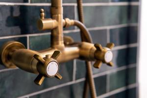 un robinet de salle de bains en bronze avec une horloge. dans l'établissement Résidence St Marc - L'Art Déco - Centre ville, à Quimper