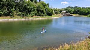 a person standing on a paddle board in the water at Chata Tokarka - Richňavské jazerá in Štiavnické Bane