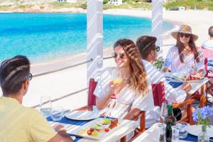 een groep mensen die aan een tafel zitten met een glas wijn bij Hotel Marinedda Thalasso & Spa in Isola Rossa