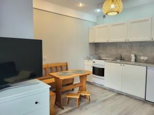 a kitchen with a wooden table and a kitchen with a tv at Apartament ORKAN przy Krupówkach in Zakopane