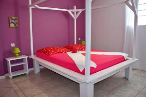 a bedroom with a canopy bed with red and white sheets at Domaine Macabou in Le Vauclin