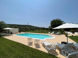 a swimming pool with lounge chairs and an umbrella at Villa Antonella in Carlentini