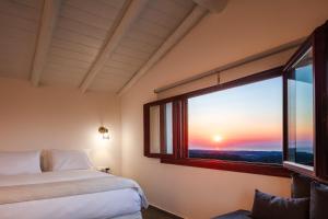 una camera con un letto e una finestra con un tramonto di Malvasia Villa a Skouloúfia