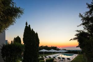 una piscina con sillas y sombrillas al atardecer en Malvasia Villa, en Skouloúfia