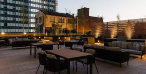 um pátio no último piso com mesas, cadeiras e edifícios em The Mercian Luxury Apartments Birmingham City Centre - Your Perfect Stay Apart hotels- 24 Hour Gym Rooftop Terrace Cinema Room em Birmingham