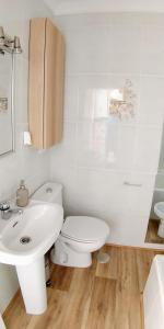 a white bathroom with a toilet and a sink at Casa Vistas a Trafalgar sólo familias o parejas - Parking privado opcional - in Conil de la Frontera