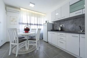 - une cuisine avec des placards blancs, une table et des chaises dans l'établissement Clock Tower Lux Apartment, à Podgorica
