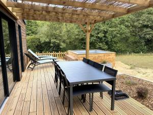 une terrasse en bois avec une table et des chaises ainsi qu'une piscine dans l'établissement La Cabane du Petit Moulin, à Bressuire