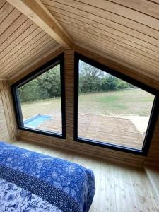 ein Schlafzimmer mit zwei großen Fenstern in einem Haus in der Unterkunft La Cabane du Petit Moulin in Bressuire