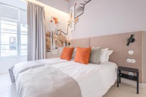 een slaapkamer met een groot wit bed met oranje kussens bij LODO Suits Ala - Studio mezanino by HD in Faro