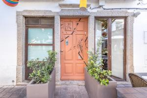LODO Suits Ala - Studio mezanino by HD في فارو: باب برتقالي على مبنى يحتوي على نباتات الفخار