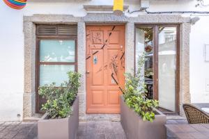 an orange door on a building with potted plants at LODO Suits Se - Mezanino room by HD in Faro