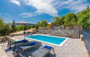 a swimming pool with two chairs and an umbrella at Awesome Home In Zmijavci With Outdoor Swimming Pool, Wifi And 2 Bedrooms in Zmijavci