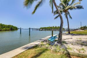 a beach with two palm trees and a pier at Bradenton Vacation Rental Gas Grill and Water Views in Bradenton