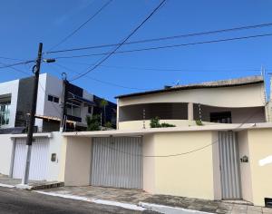 ein weißes Gebäude mit zwei Garagentüren auf einer Straße in der Unterkunft Casa 3 suítes com piscina in Natal