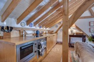 a kitchen with wooden cabinets and a stove top oven at Manor Farm Barn in Oundle