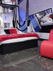 a bedroom with a bed and a red chair at La suite Miroir, Love Room in Bouc-Bel-Air