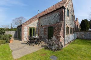 a brick building with a table and chairs in a yard at Chaff House, Rookery Farm in West Beckham