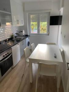 uma cozinha com uma mesa branca e cadeiras em Carcavelos Beach Five Guests apartment em Oeiras
